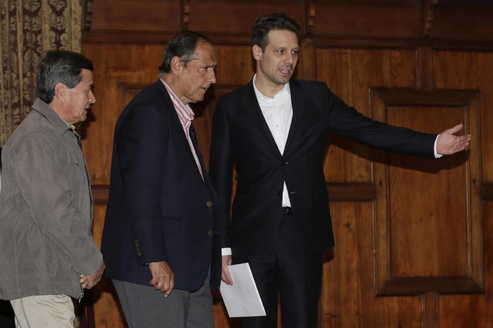 El canciller ecuatoriano, Guillaume Long, derecha, indica el camino al representante del gobierno colombiano, Juan Camilo Restrepo, al centro, y al representante de la guerrilla, Pablo Beltrán, del Ejército de Liberación Nacional (ELN), izquierda, para una conferencia de prensa conjunta en Quito, Ecuador, el miércoles 18 de enero de 2017. El segundo grupo guerrillero más grande de Colombia ha accedido a liberar a un político prominente que ha mantenido cautivo casi un año, permitiendo que así avancen los diálogos el mes entrante. (AP Foto/Dolores Ochoa)