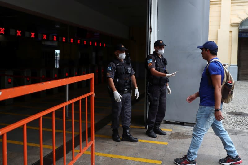 Police officers wearing protective face masks stop a passenger to check his documents before entering the ferry station to go to Niteroi, amid the coronavirus disease (COVID-19) outbreak, in Rio de Janeiro