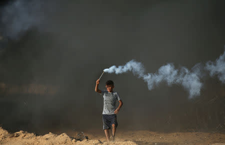 A Palestinian boy holds a tear gas canister fired by Israeli troops during a protest calling for lifting the Israeli blockade on Gaza and demanding the right to return to their homeland, at the Israel-Gaza border fence in the southern Gaza Strip October 5, 2018. REUTERS/Ibraheem Abu Mustafa