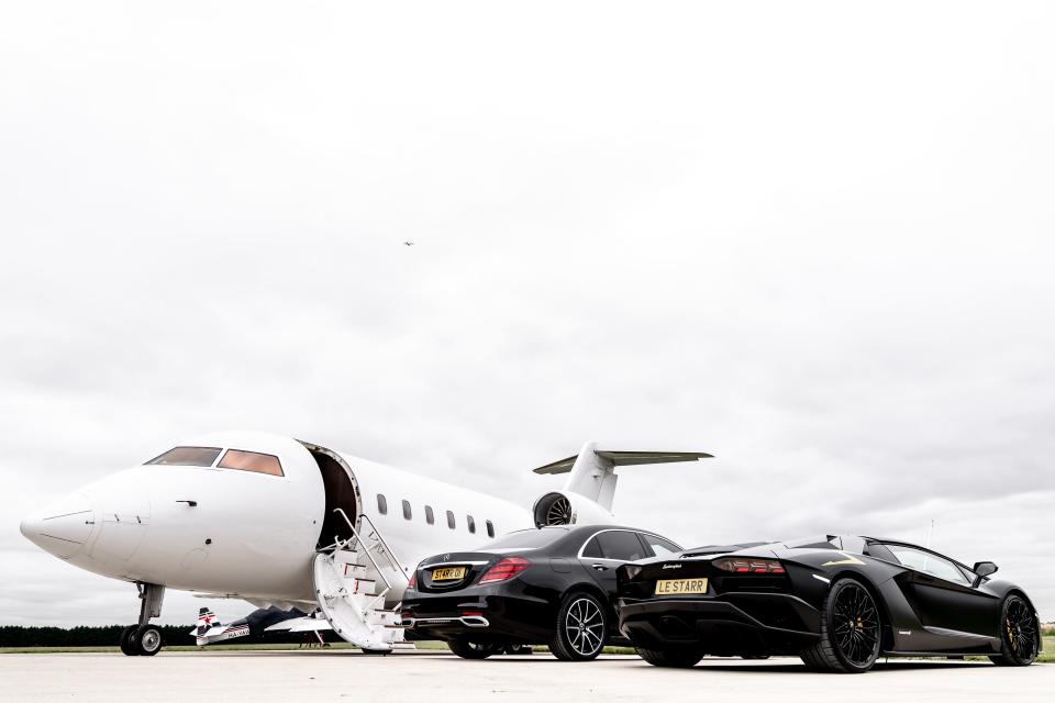 A view of two luxury cars and a private jet.