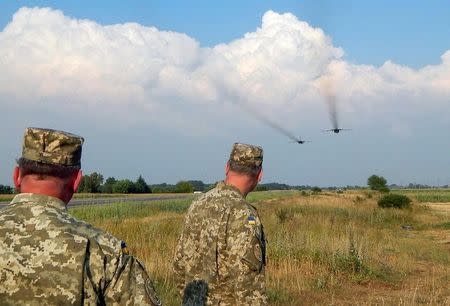 Ukrainian servicemen watch Sukhoi Su-24 front-line bombers fly during military aviation drills as Russia accuses Ukraine in incursion into annexed Crimea, in Rivne region, Ukraine, August 10, 2016. Picture taken August 10, 2016. REUTERS/Stringer