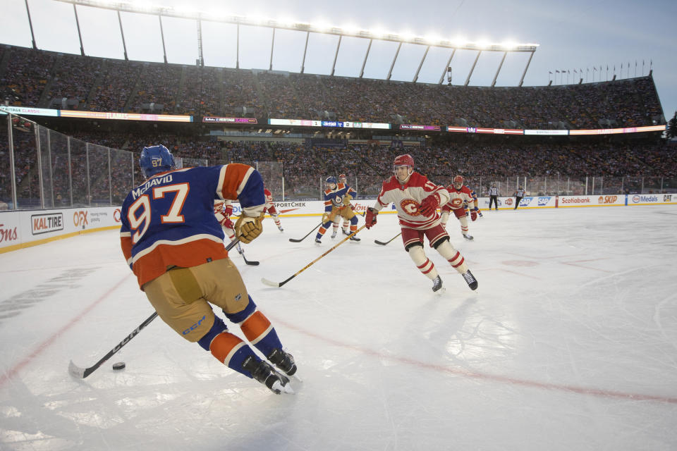 Calgary Flames' Yegor Sharangovich (17) puts pressure on Edmonton Oilers' Connor McDavid (97) during first-period NHL Heritage Classic outdoor hockey game action in Edmonton, Alberta, Sunday, Oct. 29, 2023. (Jason Franson/The Canadian Press via AP)