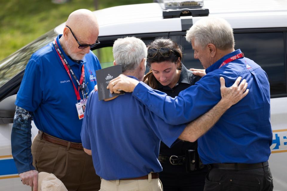 A Nashville police officer joins others in prayer outside the school on Tuesday - JAMES BREEDEN