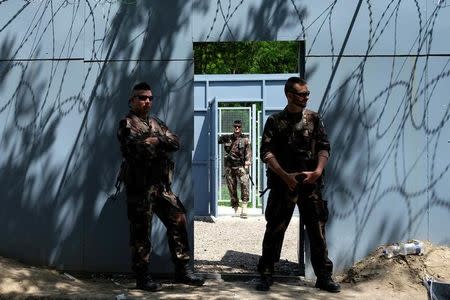 Hungarian army soldiers stand guard at the Serbian-Hungarian border fence at a makeshift camp near the village of Horgos, Serbia, June 14, 2016. REUTERS/Marko Djurica