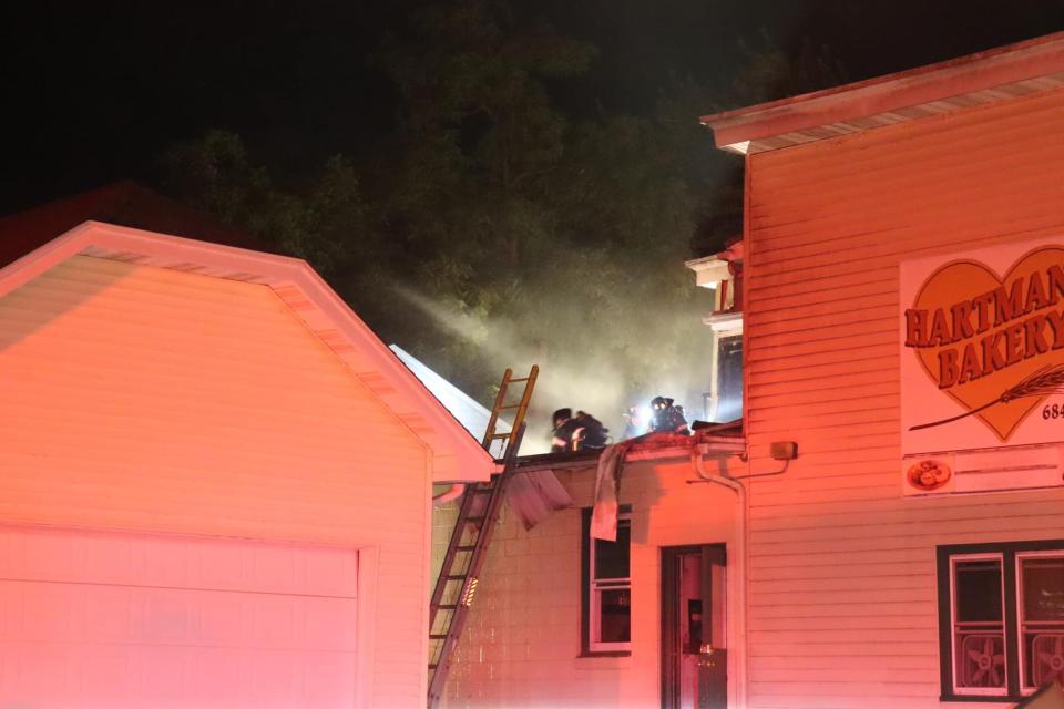 Fire crews remove roofing from Hartman's Bakery's Manitowoc location to extinguish a fire at 12:30 a.m. July 27, 2022, in Manitowoc, Wis.