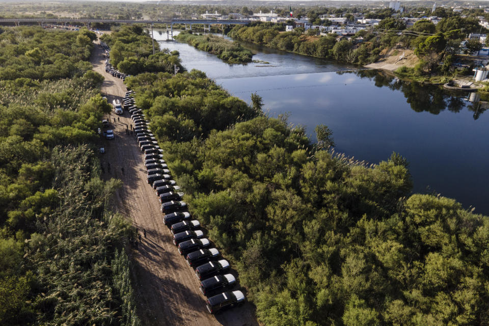 FILE - A line of Texas Department of Safety vehicles line up on the Texas side of the Rio Grande with Mexico visible, right, near an encampment of migrants, many from Haiti, Wednesday, Sept. 22, 2021, in Del Rio, Texas. (AP Photo/Julio Cortez, File)