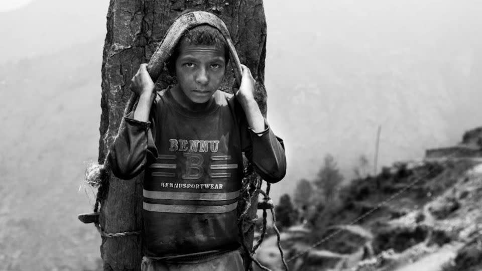 A young boy in Nepal carrying a stone weighing more than his own body. - Lisa Kristine