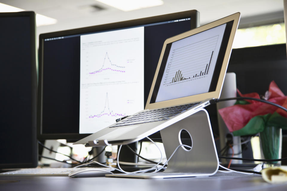 Schreibtisch mit Macbook auf Laptop-Stand, Bildschirm, Kabel