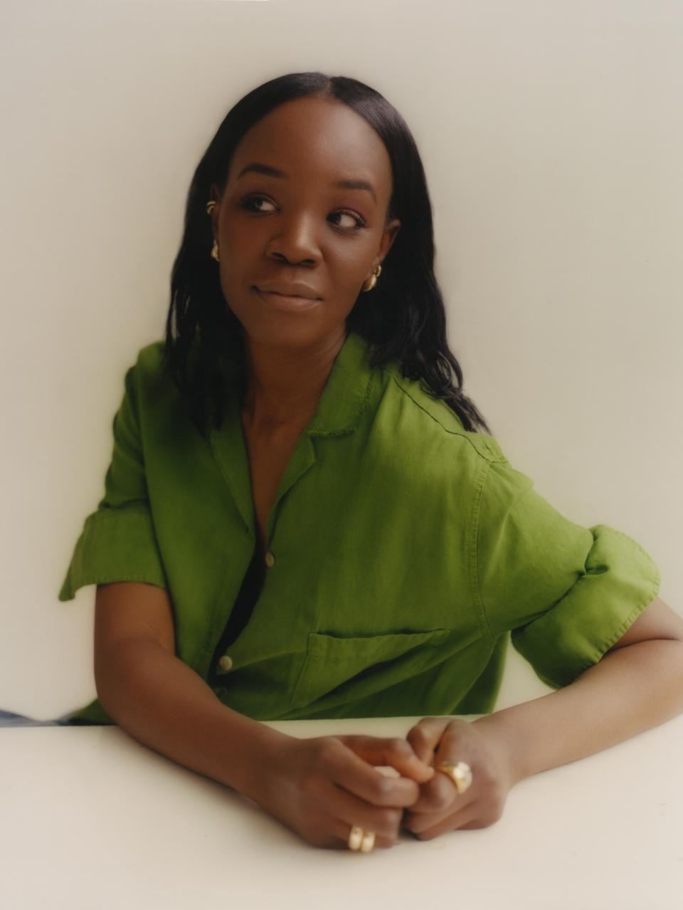 A portrait of Recho Omondi in a green blouse on a white background