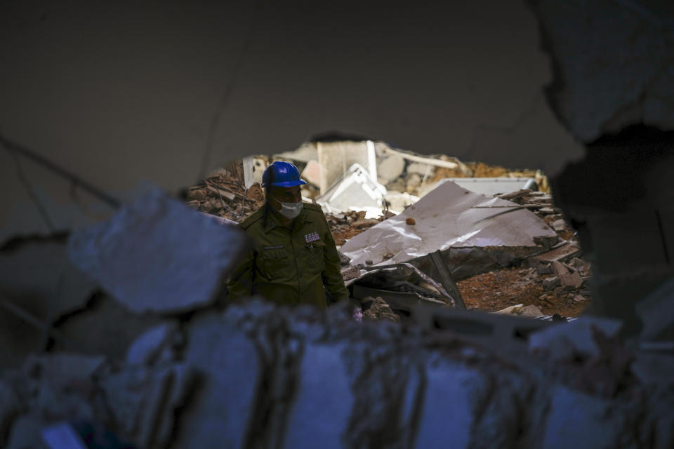 A military officer surveys the Hotel Saratoga, seen through a gap in a wall of the Calvary Baptist Church, days after a deadly explosion devastated the hotel and badly damaged the church, in Old Havana, Cuba, Wednesday, May 11, 2022. Parts of the upper floors have collapsed at the building that houses not only the church but a seminary and the denomination's headquarters for western Cuba. (AP Photo/Ramon Espinosa)