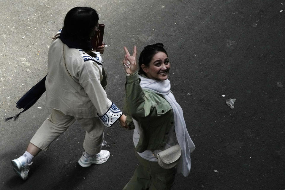 An Iranian woman without wearing her mandatory Islamic headscarf flashes a victory sign as she walks at the old main bazaar of Tehran, Iran, Thursday, June 13, 2024. (AP Photo/Vahid Salemi)