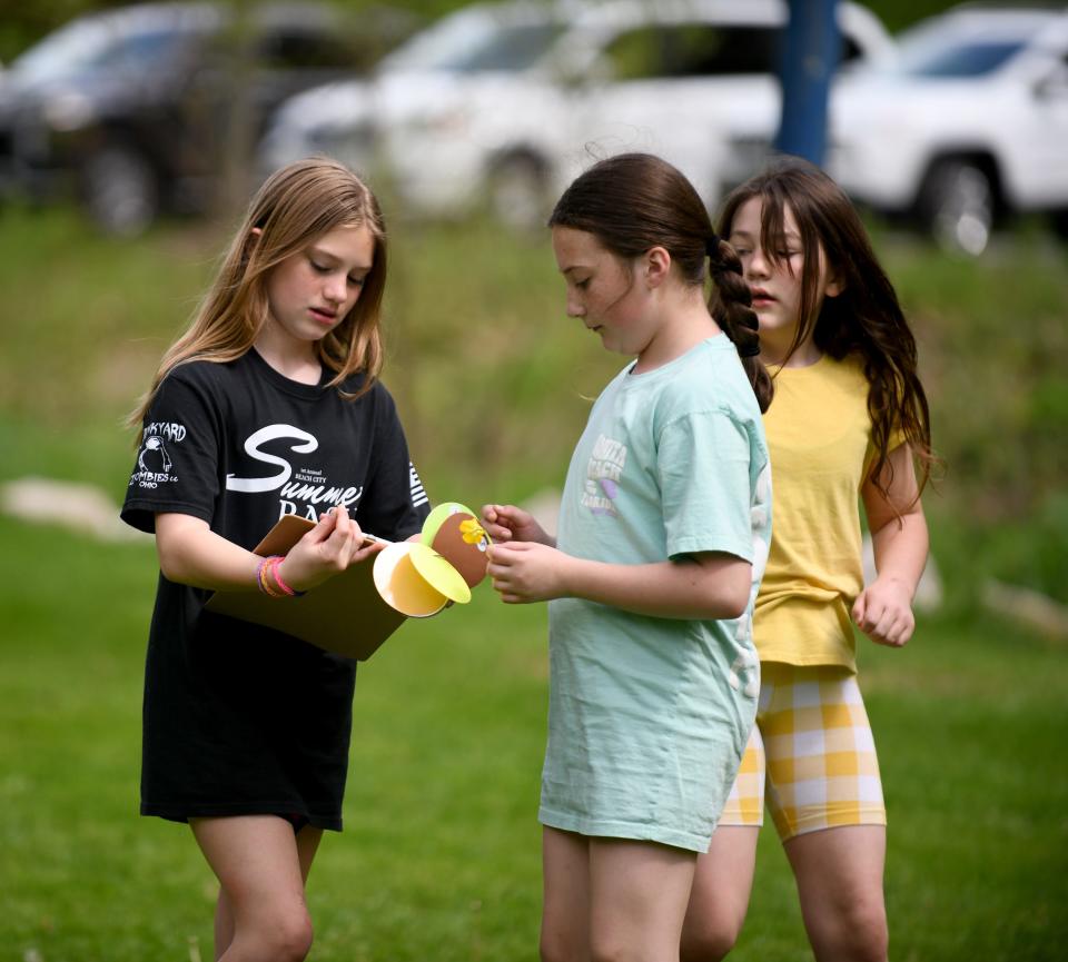 Fairless fifth graders Peyton McKague, 11, Brielle Garrabrant, 11, and Gracie Haines, work on a search activity during an outing at Navarre-Bethlehem Township Park. The students created art representing the history of Navarre as part of an art installation put in at the park. The students painted more than 90 acrylic paintings of buildings and other village history that were placed on a two-dimensional, 16-foot canal boat on display.