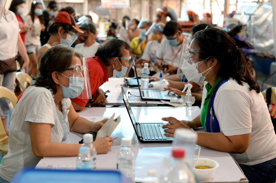 A health worker verifies a senior citizen's information prior to receiving her first dose of the coronavirus disease (COVID-19) vaccine, at a covered court in Manila, Philippines, March 29, 2021. REUTERS/Lisa Marie David