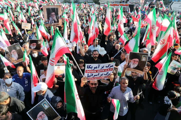 Pro-government protesters hold Iranian flags at a rally.