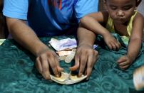 A card dealer shuffles a deck next to his son during a local version of poker known as "pusoy", in Angeles city, north of Manila, Philippines, May 22, 2015. When paying your final respects for a relative or friend, the last thing you might expect to see at the wake is people placing bets on a card game or bingo. Not in the Philippines. Filipinos, like many Asians, love their gambling. But making wagers on games such as "sakla", the local version of Spanish tarot cards, is particularly common at wakes because the family of the deceased gets a share of the winnings to help cover funeral expenses. Authorities have sought to regulate betting but illegal games persist, with men and women, rich and poor, betting on anything from cockfighting to the Basque hard-rubber ball game of jai-alai, basketball to spider races. Many told Reuters photographer Erik De Castro that gambling is only an entertaining diversion in a country where two-fifths of the population live on $2 a day. But he found that some gamble every day. Casino security personnel told of customers begging to be banned from the premises, while a financier who lends gamblers money at high interest described the dozens of vehicles and wads of land titles given as collateral by those hoping lady luck would bring them riches. REUTERS/Erik De Castro TPX IMAGES OF THE DAY PICTURE 19 OF 29 FOR WIDER IMAGE STORY "HIGH STAKES IN MANILA". SEARCH "BINGO ERIK" FOR ALL IMAGES.