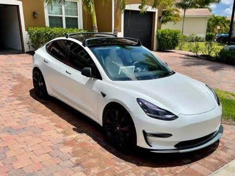 A pearl white Model 3 Tesla parked in a driveway