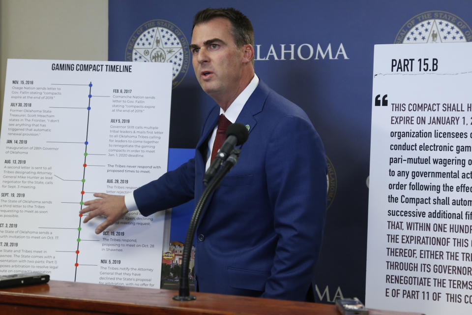 Oklahoma Gov. Kevin Stitt gestures to a sign concerning the renewal of Tribal Gaming Compacts during a news conference Thursday, Nov. 14, 2019, in Oklahoma City. (AP Photo/Sue Ogrocki)