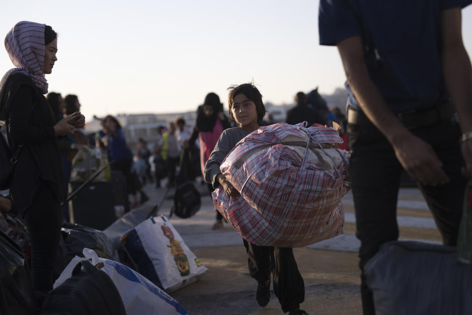 Refugees and migrants carry their belongings after they disembark from a ferry, at the port of Piraeus, near Athens, Tuesday, Sept. 25, 2018. About 400 migrants and refugees arrived at the port from the island of Lesbos as authorities have been moving hundreds of migrants deemed to be vulnerable from the overcrowded Moria camp to camps on the mainland. (AP Photo/Petros Giannakouris)