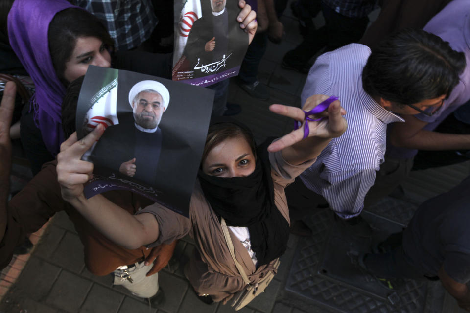 A female supporter of Iranian presidential candidate Hassan Rouhani, flashes a victory sign as she holds his poster during a celebration gathering in Tehran, Iran, Saturday, June 15, 2013. (AP Photo/Vahid Salemi)