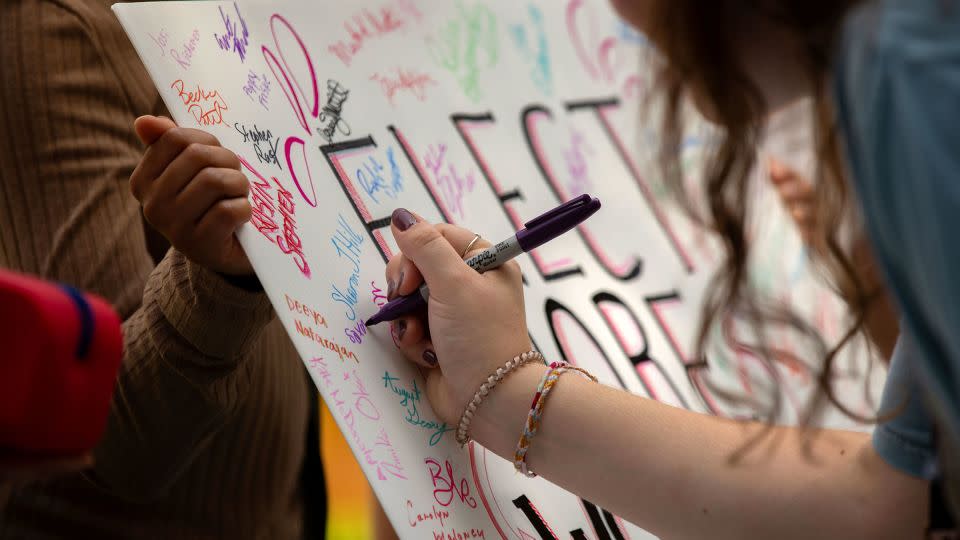 People sign a poster that reads "Elect More Women" during the Democratic rally in Glen Allen, Virginia, on September 9, 2023. - Rebecca Wright/CNN