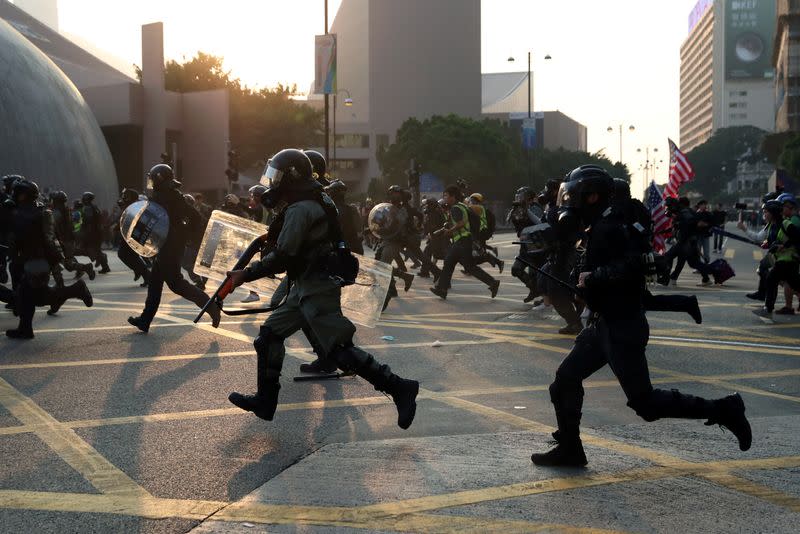 Riot police officers charge towards anti-government protesters during the "Lest We Forget" rally in Hong Kong