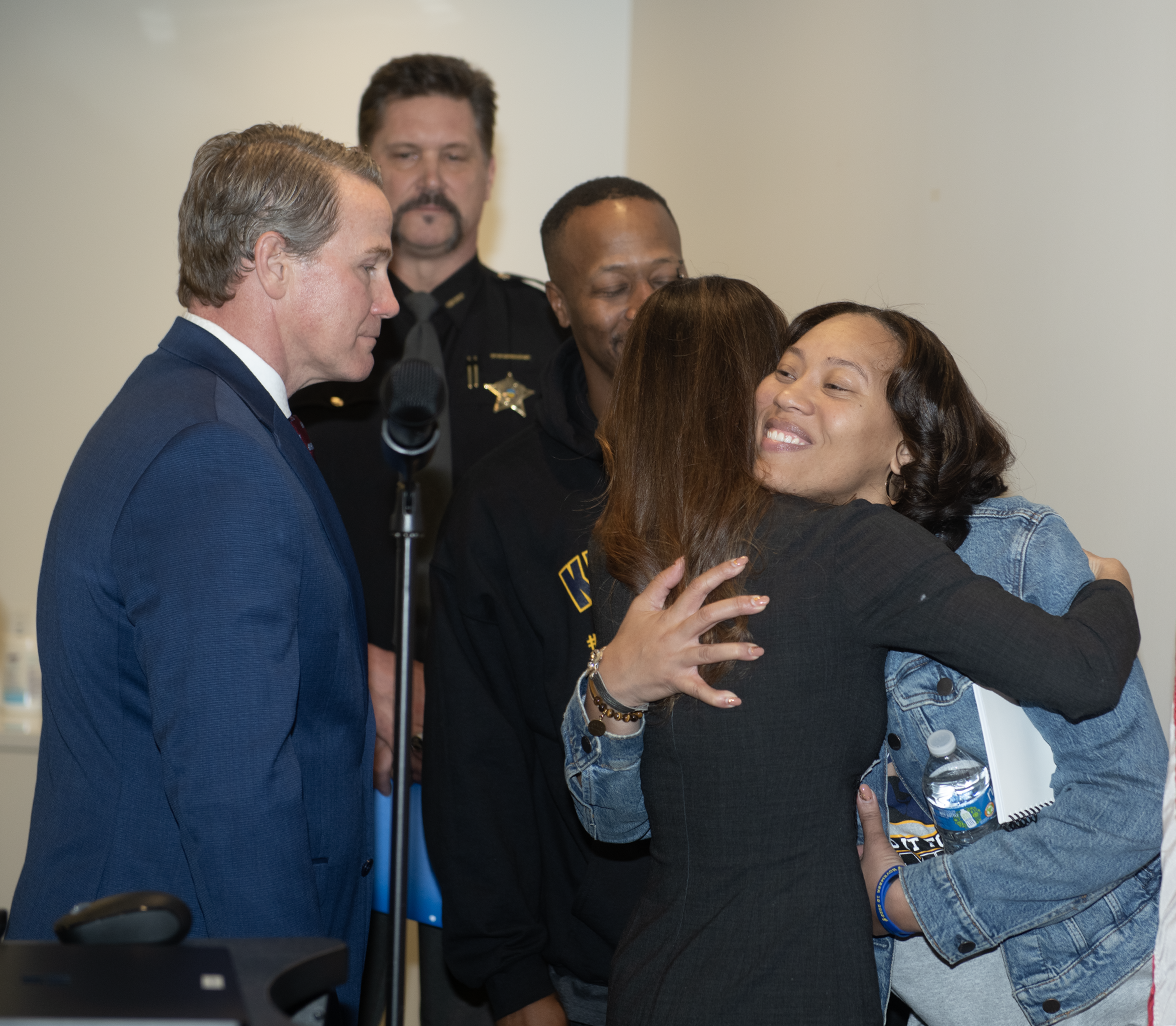 Tina Husted hugs Tamia Woods, whose 17-year-old son, James, died by suicide after he became a sextortion victim. Lt. Gov. Jon Husted, left, held a press conference Thursdayon the Social Media Parental Notification Act at Educational Service Center of Northeast Ohio in Independence. Portage County Sheriff Bruce Zuchowski stands at back and Woods' husband, Tim Woods, is behind Tina Husted and Woods.