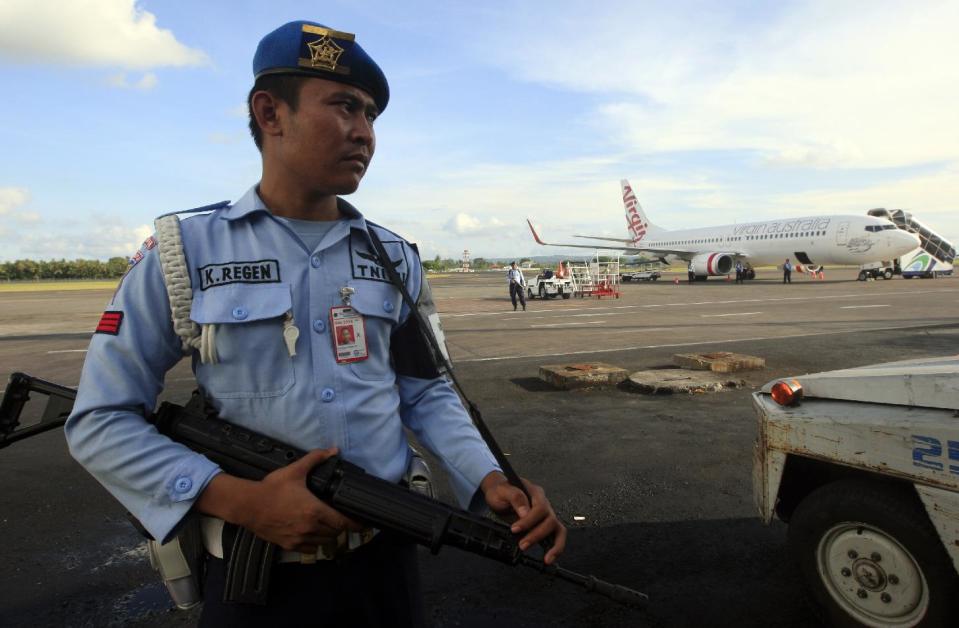 An Indonesian Air Force member stands guard near a Virgin Australia airplane in Bali, Indonesia, Friday, April 25, 2014. A drunken passenger who caused a hijack scare on a Virgin Australia flight by trying to break into the cockpit was arrested Friday after the plane landed on Indonesia's resort island of Bali, officials said. (AP Photo/Firdia Lisnawati)