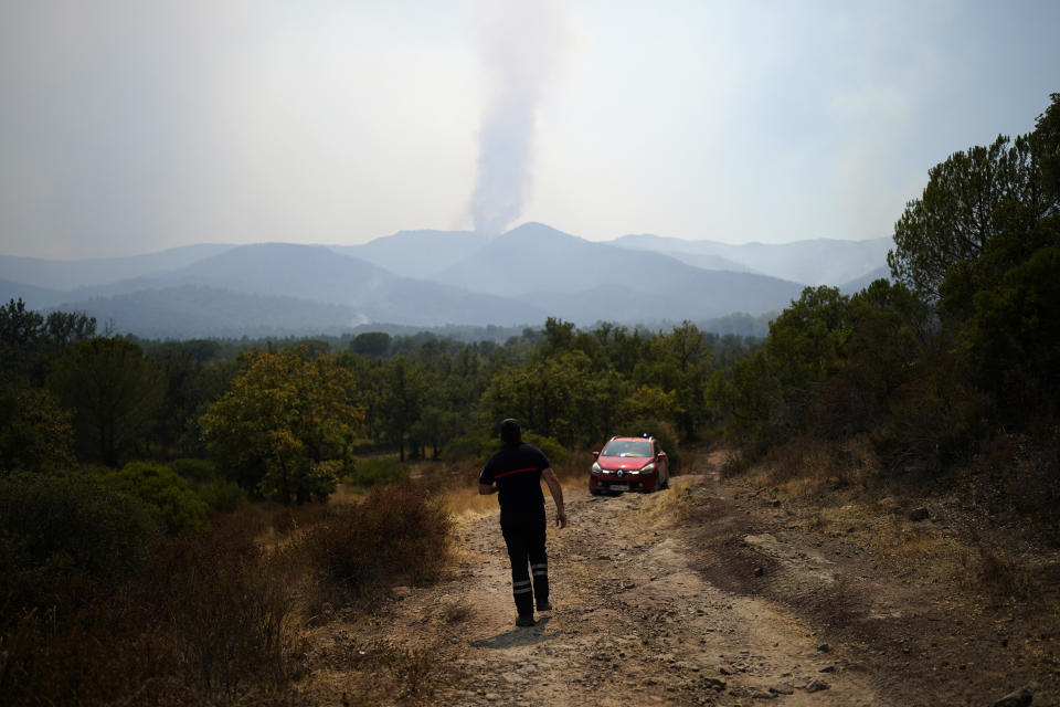 A fireman watches a fire in the distance as he patrols in a forest near Le Luc, southern France, Tuesday, Aug. 17, 2021. Thousands of people were evacuated from homes and vacation spots near the French Riviera as firefighters battled a fire racing through surrounding forests Tuesday, the latest of several wildfires that have swept the Mediterranean region.(AP Photo/Daniel Cole)