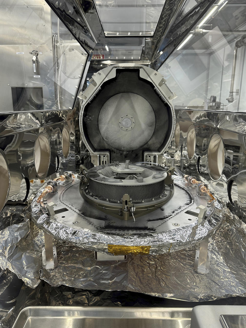 This undated photo provided by NASA, shows a view inside a glass and stainless steel glovebox containing the Osiris-Rex asteroid sample return canister at Johnson Space Center in Houston. NASA on Wednesday, Oct. 11, 2023, showed off its first asteroid samples delivered last month by a spacecraft, a jumble of black dust and rubble that's the most ever returned to Earth. (Dante Lauretta/NASA via AP)