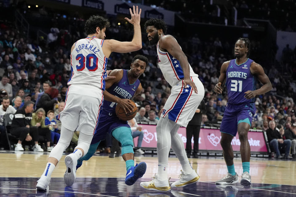 Charlotte Hornets guard Ish Smith drives to the basket between Philadelphia 76ers guard Furkan Korkmaz and center Joel Embiid during the first half of an NBA basketball game on Saturday, Jan. 20, 2024, in Charlotte, N.C. (AP Photo/Chris Carlson)