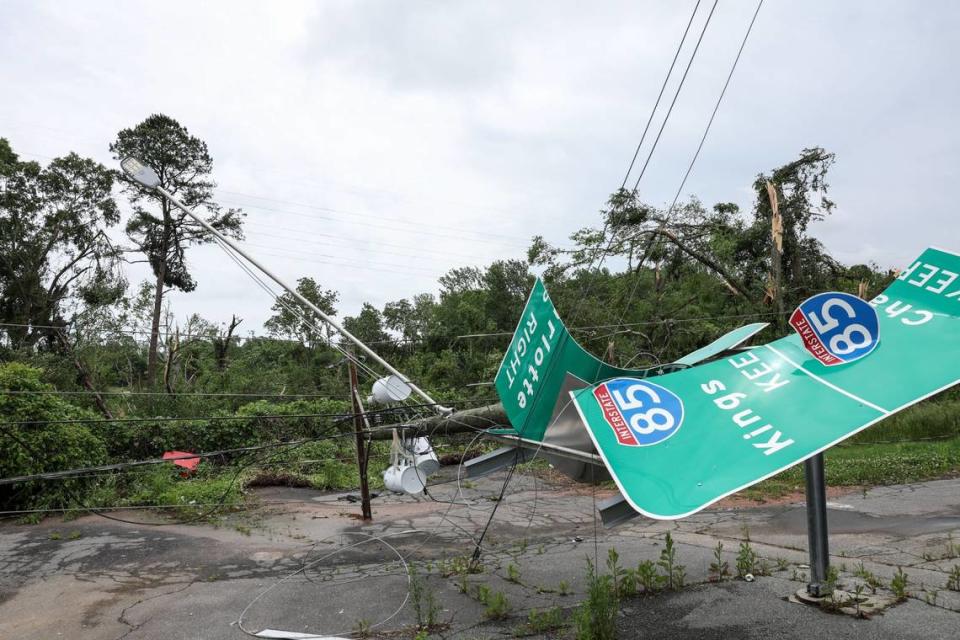 A sign for the exit onto I-85 is tangled with electrical wires from a downed utility pole along North Chester Street in Gastonia on Thursday, May 9, 2024. Storms tore through the area yesterday causing property damage and causing power outages.