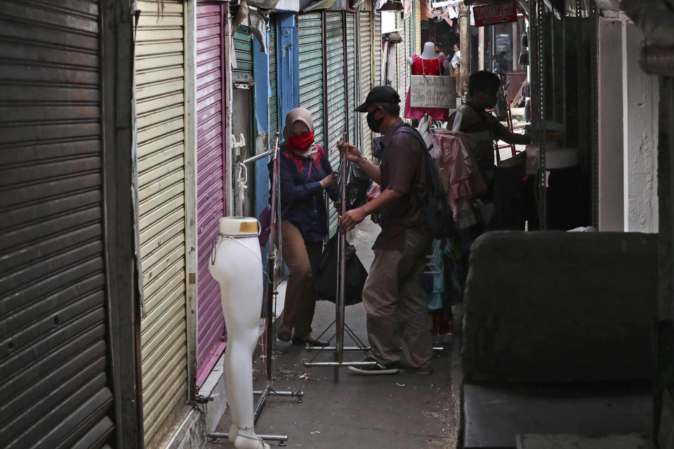 In this Thursday, April 30, 2020, photo, shop owners collect leftover items from their shop at Tanah Abang textile market that is closed due to the new coronavirus outbreak in Jakarta, Indonesia. May Day usually brings both protest rallies and celebrations rallies marking international Labor Day. This year it's a bitter reminder of how much has been lost for the millions left idle or thrown out of work due to the coronavirus pandemic. Garment workers in Asia are among the hardest hit as orders dry up and shutdowns leave factories shuttered. (AP Photo/Tatan Syuflana)