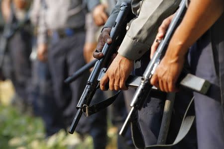 Police hold weapons as they stand guard in front of a court during the arrival of student protesters in Letpadan, March 11, 2015. REUTERS/Soe Zeya Tun