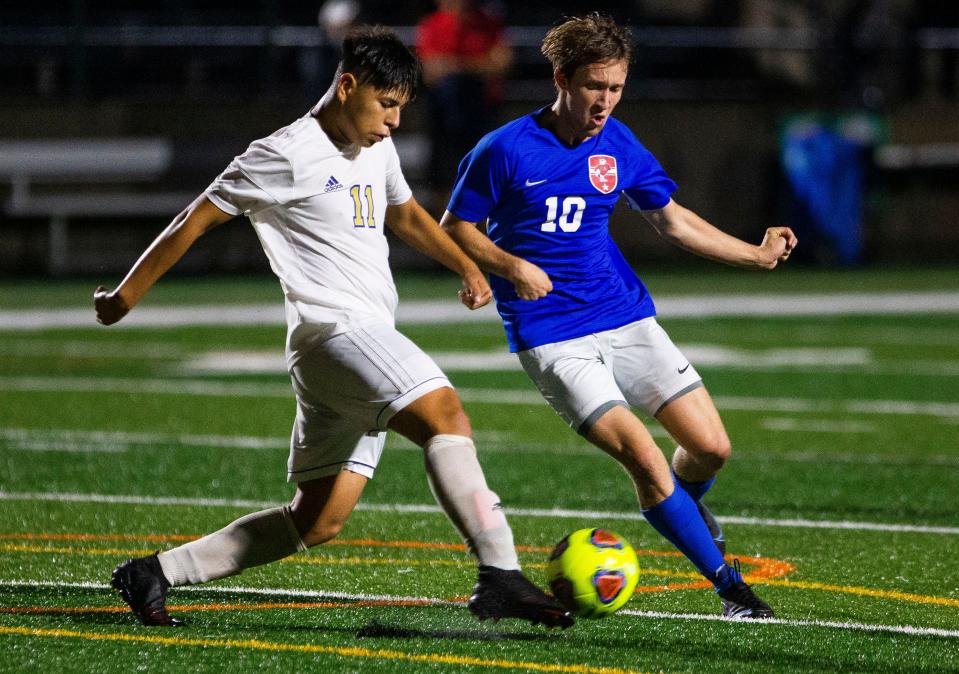 Elkhart's Jared Garcia clears the ball away from Adams' Connor McKenna during the Adams vs. Elkhart regional semifinal game Thursday, Oct. 14, 2021 at School Field in South Bend. 