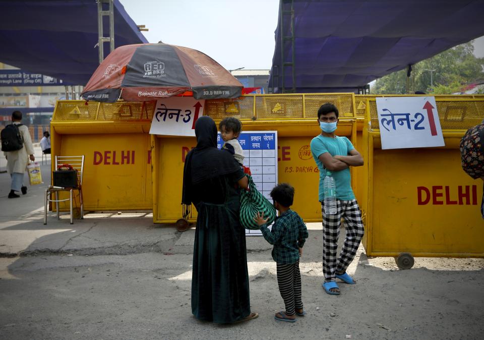 A family of migrant worker checks the train timings outside a railway station during extended lockdown in New Delhi, India, Monday, May 18, 2020. India has recorded its biggest single-day surge in new cases of coronavirus. The surge in infections comes a day after the federal government extended a nationwide lockdown to May 31 but eased some restrictions to restore economic activity and gave states more control in deciding the nature of the lockdown. (AP Photo/Manish Swarup)