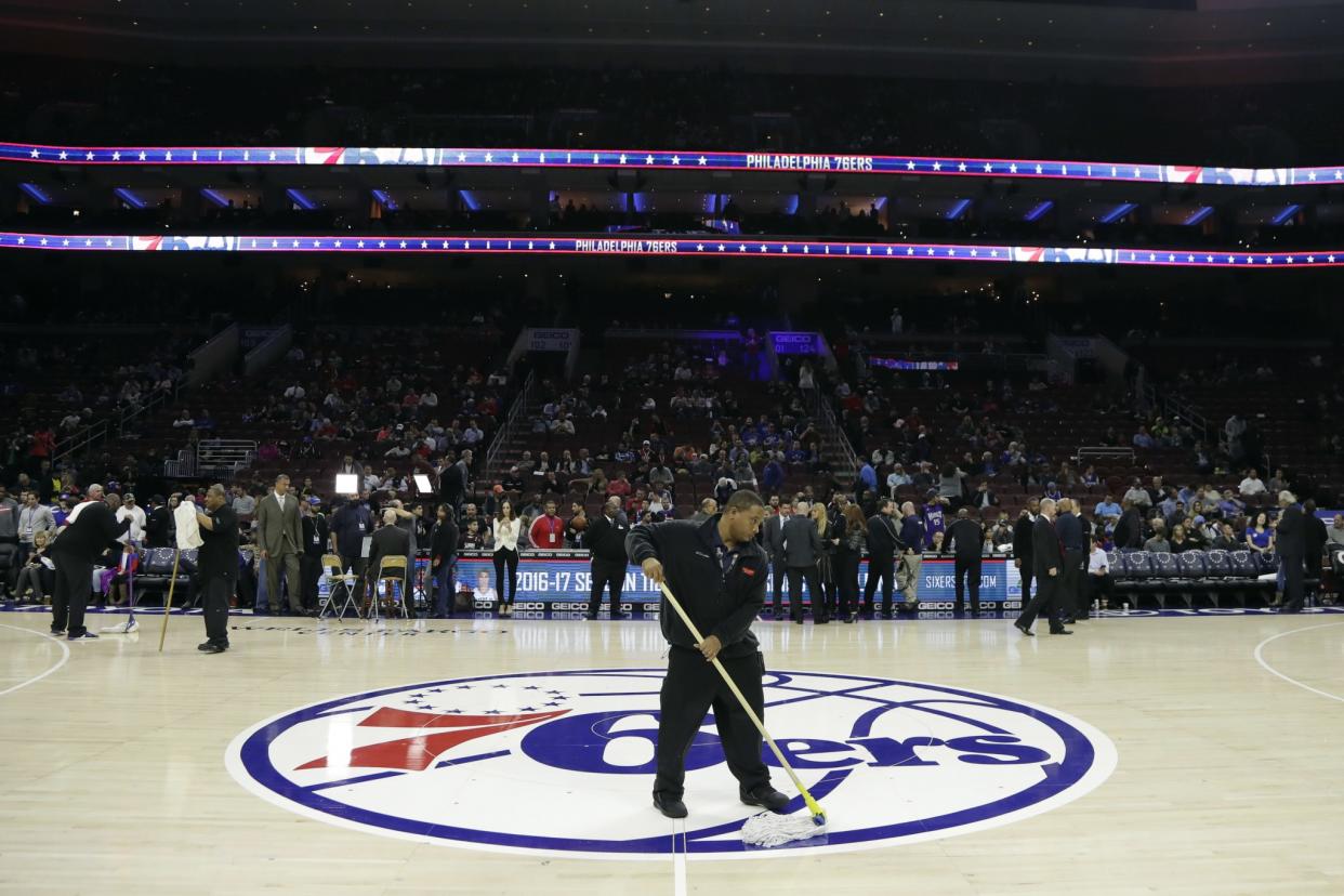 A building worker wipes the court before an NBA basketball game between the Philadelphia 76ers and the Sacramento Kings, Wednesday, Nov. 30, 2016, in Philadelphia. The start of the game was delayed due to a surface issue with the court. (AP)