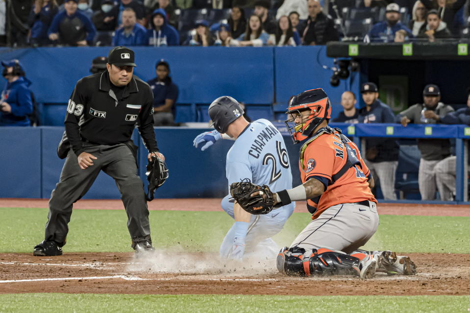 Toronto Blue Jays' Matt Chapman (26) scores on a single by second baseman Santiago Espinal (not shown) past Houston Astros catcher Martin Maldonado, right, during the seventh inning of a baseball game in Toronto, Sunday, May 1, 2022. (Christopher Katsarov/The Canadian Press via AP)