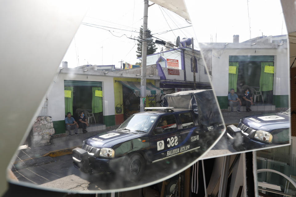 A police patrol, reflected in mirrors hanging in a shop, drives down a street where businesses were open, though reporting less customers, in Santa Cruz Xochitepec in the Xochimilco district of Mexico City, Wednesday, April 1, 2020. Mexico has started taking tougher measures against the coronavirus, but some experts warn the sprawling country of 129 million is acting too late and testing too little to prevent the type of crisis unfolding across the border in the United States. (AP Photo/Rebecca Blackwell)