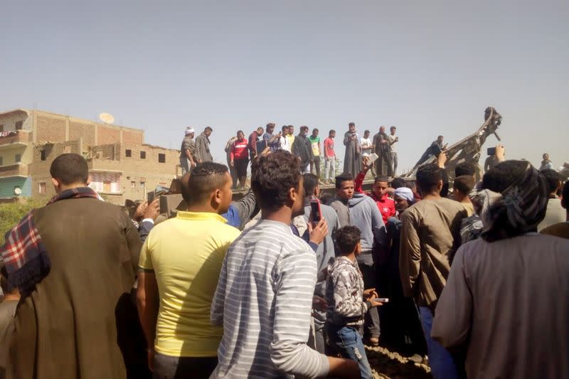 People inspect the damage after two trains have collided near the city of Sohag