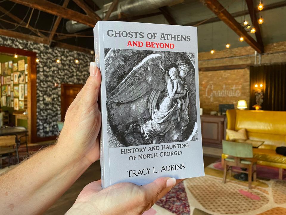 "Ghosts of Athens and Beyond" author Tracy Adkins holds a copy of her book in the lobby of the Graduate Athens on Sept. 7, 2022.