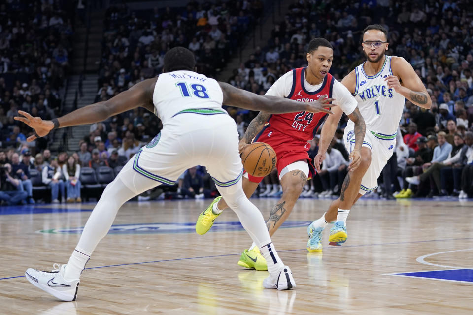 New Orleans Pelicans guard Jordan Hawkins (24) dribbles toward the basket as Minnesota Timberwolves guard Shake Milton (18) and forward Kyle Anderson (1) defend during the first half of an NBA basketball game, Wednesday, Nov. 8, 2023, in Minneapolis. (AP Photo/Abbie Parr)
