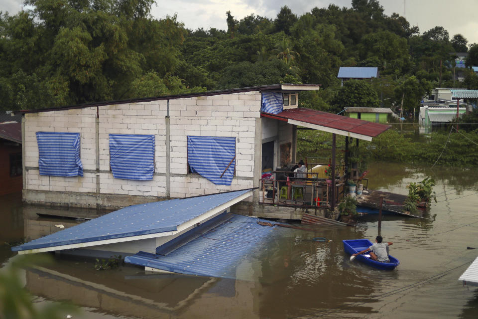 A resident paddles through floodwaters to reach the second story of his home in Ubon Ratchathani province, northeastern Thailand, Monday, Oct. 3, 2022. Heavy rainfall in northern, northeastern and central Thailand on Monday fueled severe flooding, as some areas were further threatened as the authorities had to order pressure on filled to capacity dams eased by releasing water into already overflowing rivers. (AP Photo/Nava Sangthong)