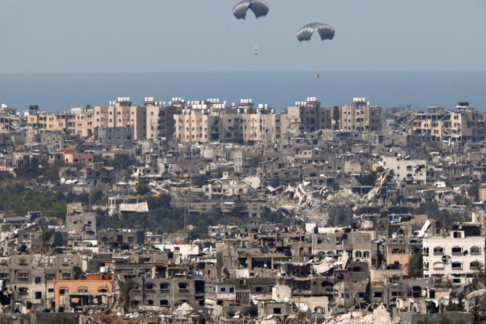 Humanitarian aid falls through the sky towards the Gaza Strip after being dropped from an aircraft (Reuters)