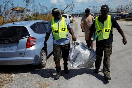 Police officers help carrying a bag at an airport during an evacuation operation after Hurricane Dorian hit the Abaco Islands in Treasure Cay