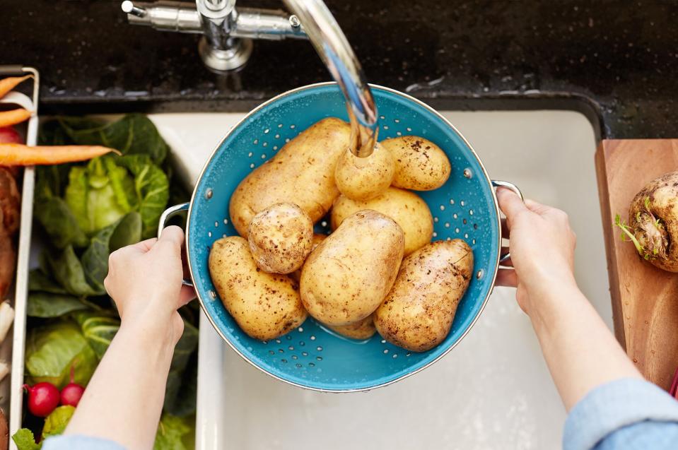 Woman washing potatoes in sink