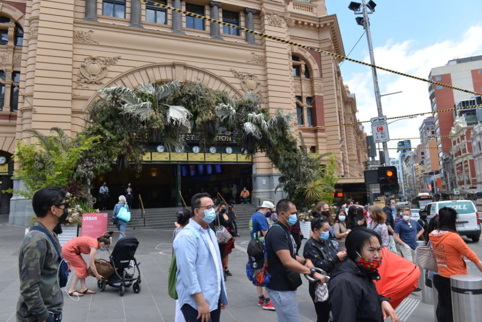 A small group of people in Melbourne wearing face masks at a traffic crossing.