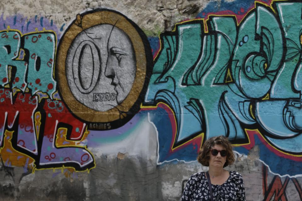A woman stands in front of graffiti depicting a zero Euro coin in Athens on Thursday, June 4, 2015.  (AP Photo/Thanassis Stavrakis)