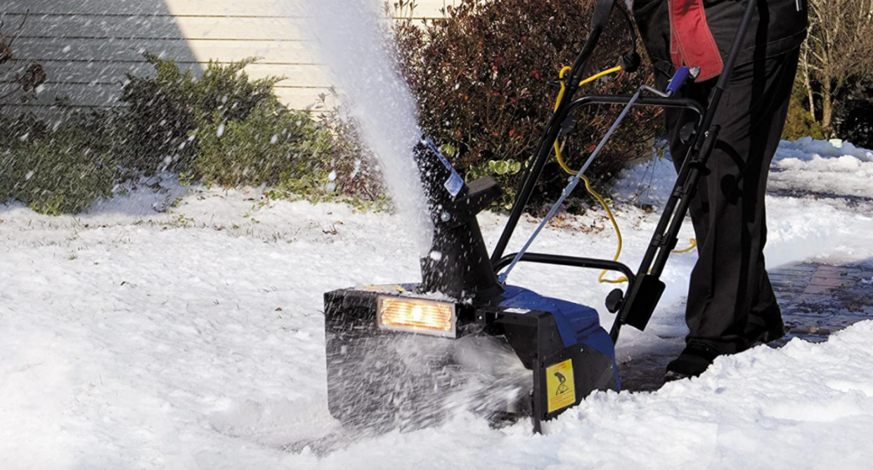 man using snow joe snow thrower to remove snow from sidewalk