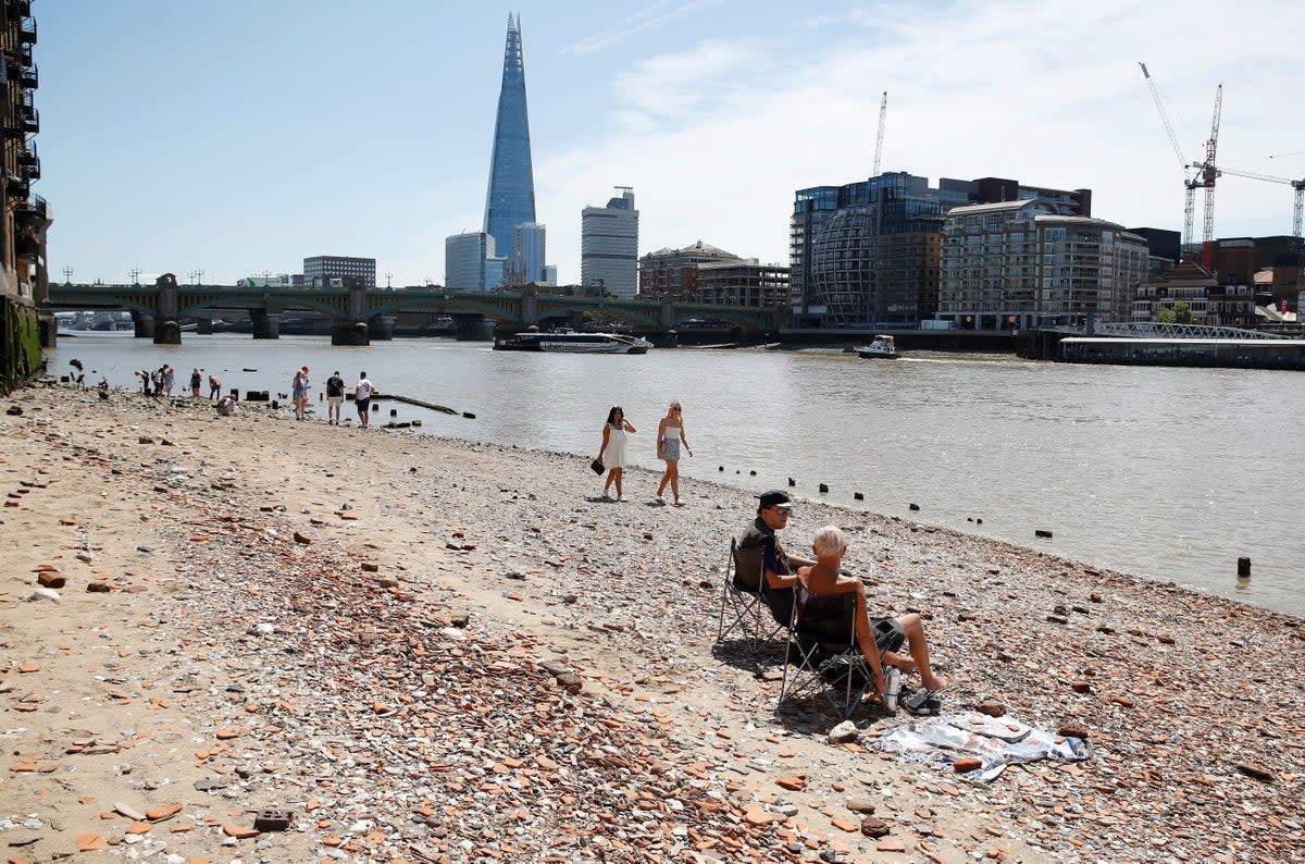 People take to a beach by the river Thames at low tide in London (REUTERS)