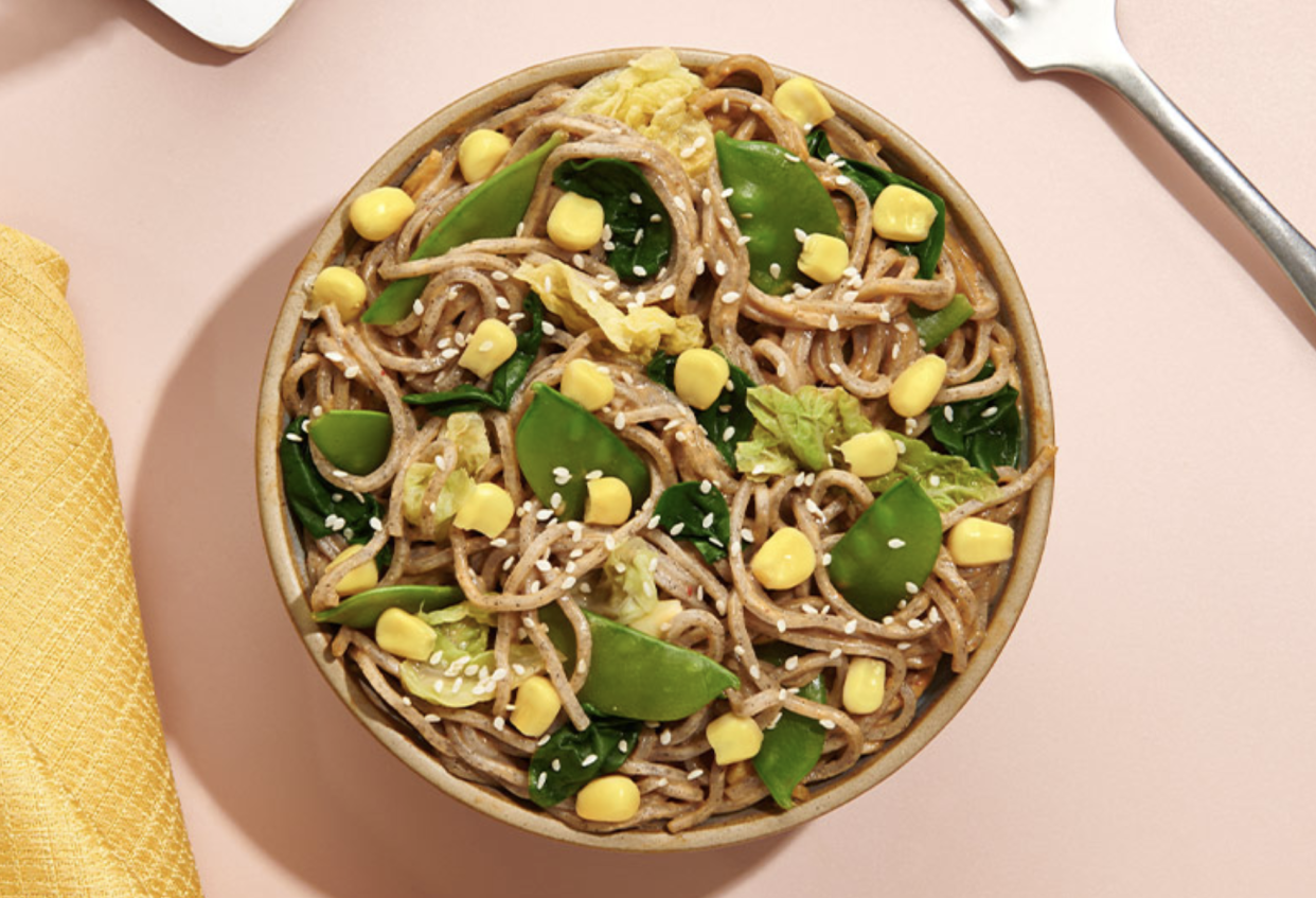 A noodle dish in a bowl on a table.